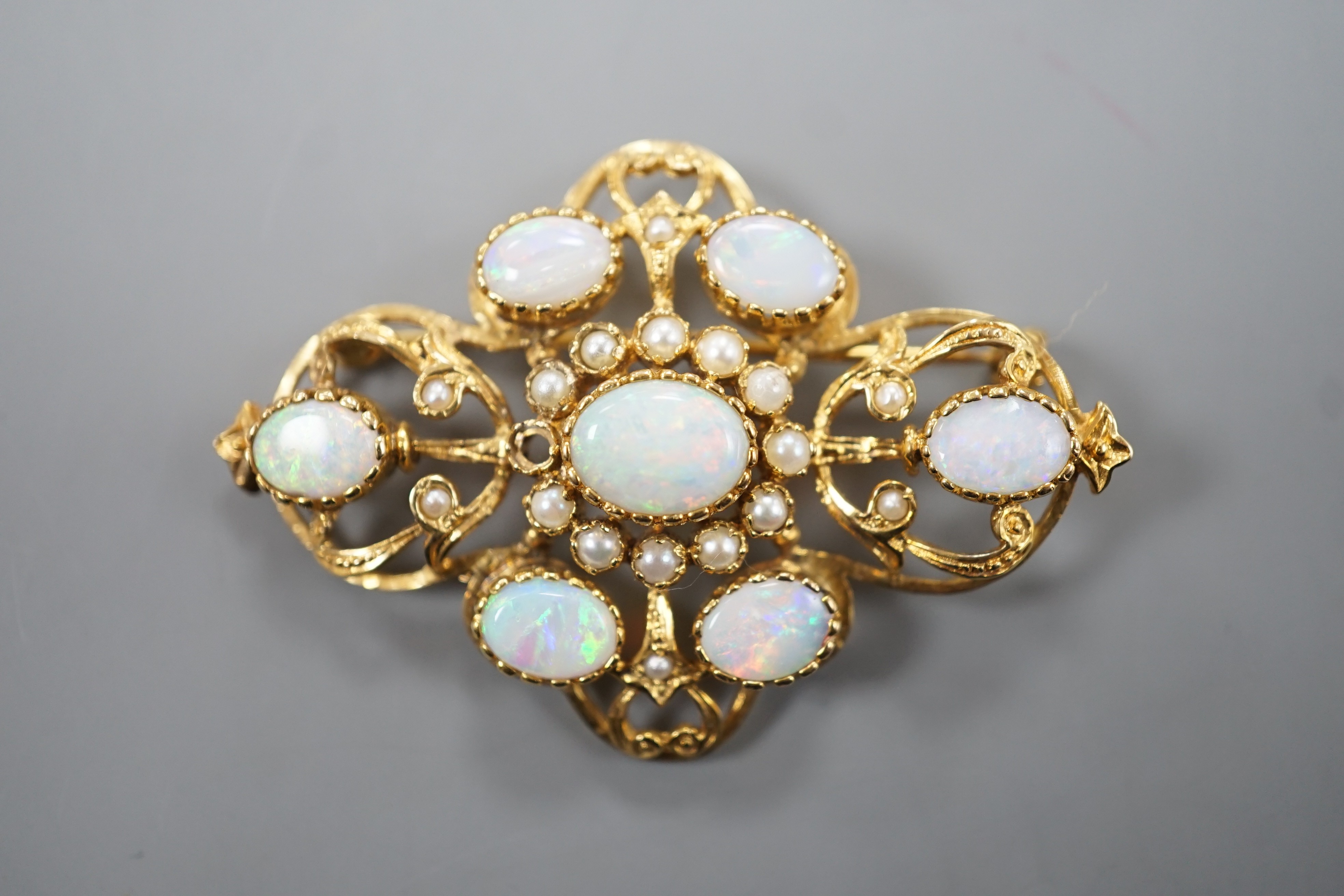 An early 1970's 9ct gold, graduated oval white opal and split pearl set brooch, of quatrefoil shape (pearl missing), 48mm, gross weight 9.3 grams.